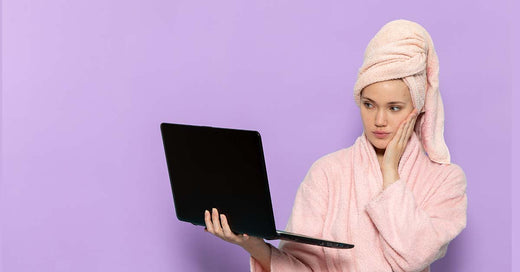 Purple background with a woman touching her face while looking to the laptop
